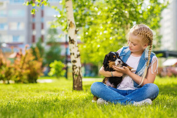 Little girl with a berner sennenhund puppy, outdoor, summer