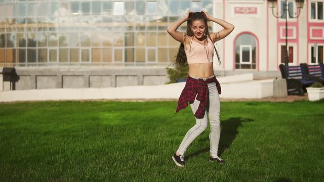 Young hipster woman with dreads turning cartwheels in a park during a bright sunny summer day. Slowmotion shot