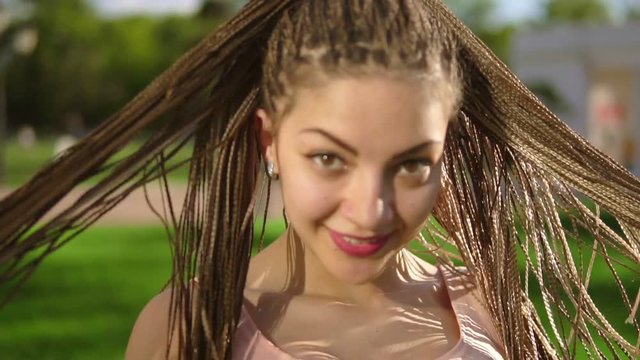 Young beautiful girl with dreads dancing in a park. Beautiful woman listening to music and dancing during a sunny day. Slowmotion shot.