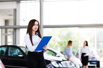 Bussines woman standing and writing on paper at modern car dealership