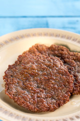 Fried minced meat burgers served on the plate above wooden blue boards