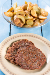 Fried minced meat burgers served on the plate above wooden blue boards