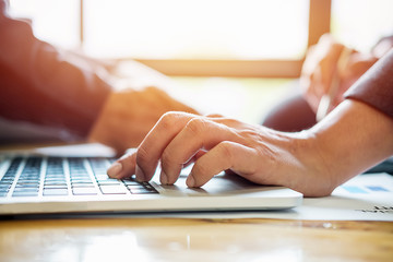 Close up young Asian Business man using laptop computer with discussion and analysis data at meeting.Close up hand on keyboard.Business finances and accounting concept.vintage tone