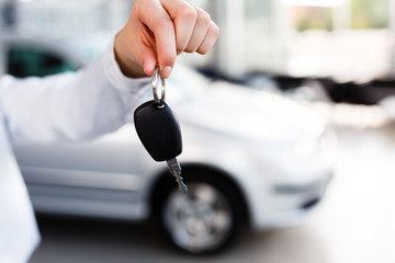 woman standing in modern car dealership and holding car key