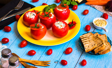 Stuffed tomatoes with cheese, and different vegetables, on a wooden background,
