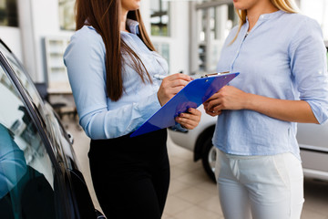 Two women makeing a agreement in modern car dealership