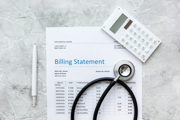 medical treatmant billing statement with stethoscope and calculator on stone background top view