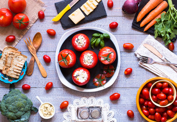 Stuffed tomatoes with cheese, and different vegetables, on a wooden background,