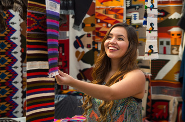 Close up of a young woman touching an andean backpack traditional clothing textile yarn and woven by hand in wool, colorful fabrics background