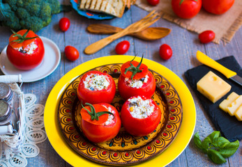 Stuffed tomatoes with cheese, and different vegetables, on a wooden background,