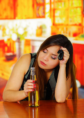 Portrait of a beautiful woman sleeping and holding her beer and her car keys on wooden table in bar background