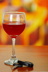 Close up of a cup of red wine with car keys on wooden table