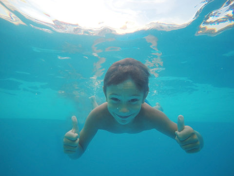 Little boy swimming underwater in pool