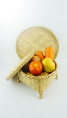 Vegetables in weaving craft basket made of pine on white background with lens flare on  the top left.