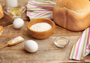 Ingredients for preparing bread in machine on wooden table