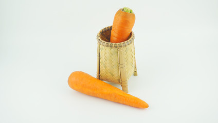 Carrots in weaving craft basket made of pine on white background.