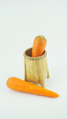 Carrots in weaving craft basket made of pine on white background.