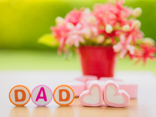 Obraz premium Father's day concept. DAD alphabet with marshmallow in the shape of heart and flower on background