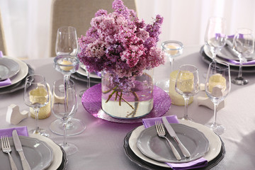 Table setting with beautiful bouquet of lilac as floral decoration and silver cutlery