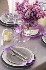 Table setting with beautiful bouquet of lilac as floral decoration and silver cutlery