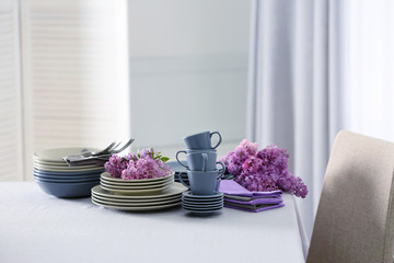 Pile of dishware and lilac blossom on table