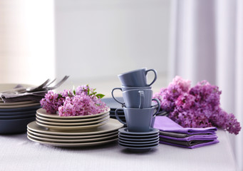 Pile of dishware and lilac blossom on table