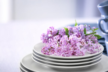Pile of dishware and lilac blossom on table