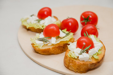 Italian bruschetta with soft cheese, tomatoes, rosemary and fresh salad on the plate. Space for text