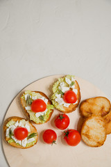 Italian bruschetta with soft cheese, tomatoes, rosemary and fresh salad on the plate. Space for text