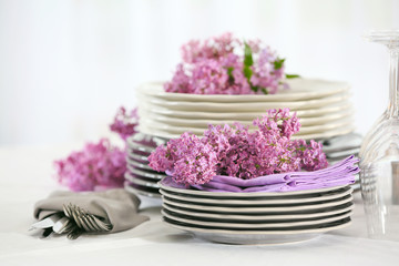 Fototapeta na wymiar Pile of dishware and lilac blossom on table