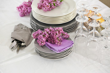 Pile of dishware and lilac blossom on table