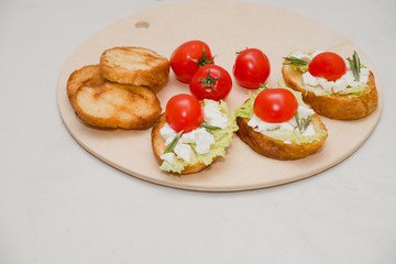 Italian bruschetta with soft cheese, tomatoes, rosemary and fresh salad on the plate. Space for text
