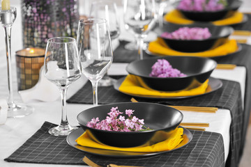 Beautiful table setting with black plates and lilac as floral decor