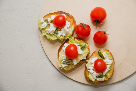 Italian bruschetta with soft cheese, tomatoes, rosemary and fresh salad on the plate. Space for text