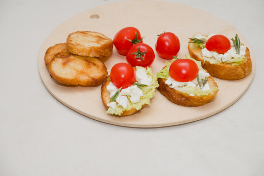Italian bruschetta with soft cheese, tomatoes, rosemary and fresh salad on the plate. Space for text