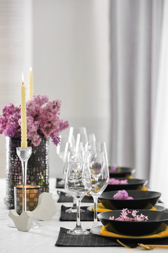 Beautiful table setting with black plates and lilac as floral decor