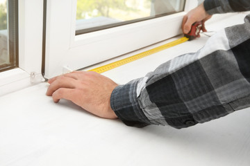Young man installing window shades at home