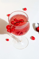 Pink champagne wine jelly with red currant in a glass, bright daylight, on white background. Top view. Copy space