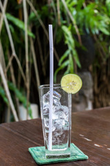 Glass with ice cubes and lime on a tropical background. Bali island.