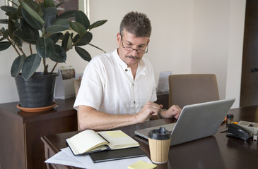 middle aged man working at this computer at his home office