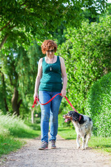 mature woman with Brittany dog at the leash