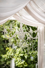 Outdoor scene with chandelier, overgrown with greenery. Rustic style. 