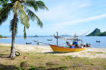 Beachfront scenery with fishing boats landing at Prachuap Khiri Khan, Thailand.