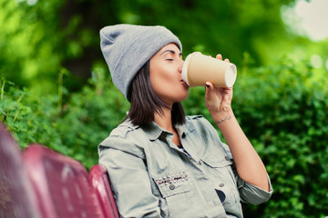 Female drinks coffee  in a summer park.