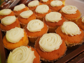 rows of cup cakes in on shelf in bakery or baker's shop