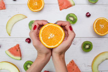 Top view of girl's hands, placed on white desktop with fruits.