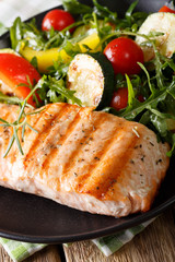 Grilled fillet of salmon with a salad of zucchini, arugula, peppers and tomatoes close-up. Vertical