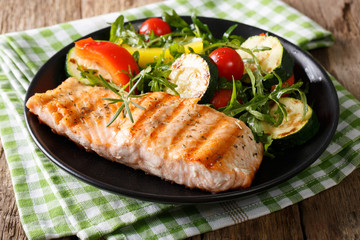grilled salmon fillet with salad of zucchini, arugula, pepper and tomatoes close-up. horizontal