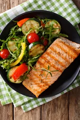  Grilled fillet of salmon with a salad of zucchini, arugula, peppers and tomatoes close-up. vertical top view © FomaA