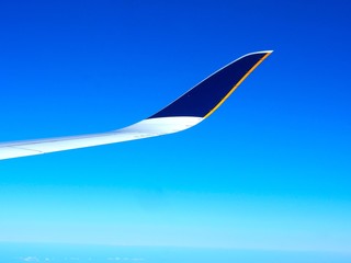 Naklejka na ściany i meble Aircraft wing on flight to travel in the atmosphere with navy blue sky background.